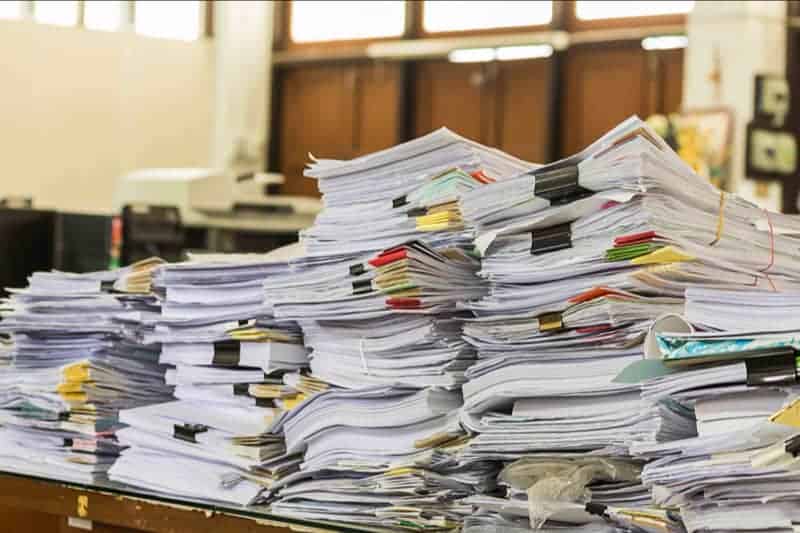 A pile of documents on a table represents the bureaucracy which the state may use to suppress the right to private property