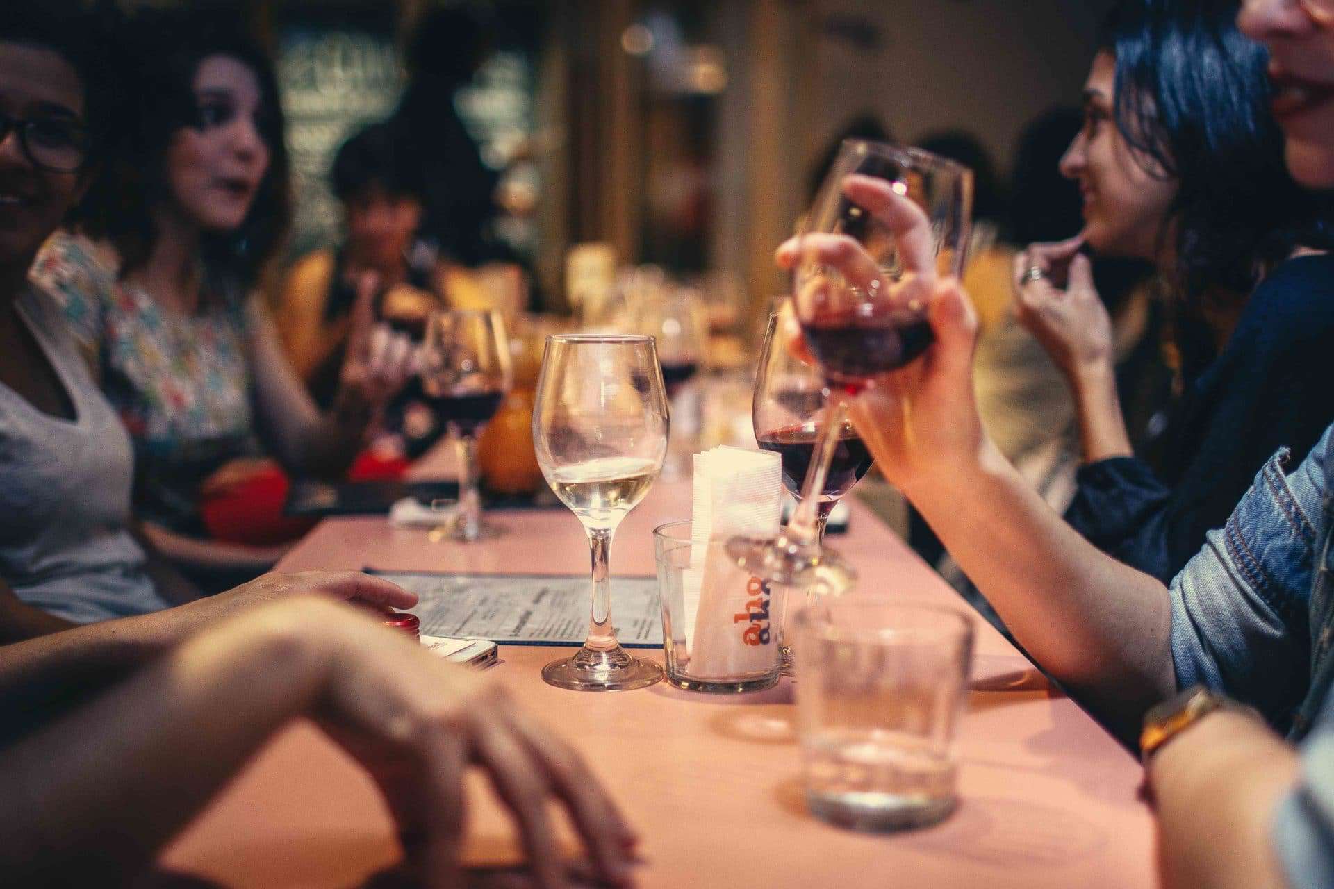 People drink wine at a dinner table, showing the personal level at which consumerism could affect us