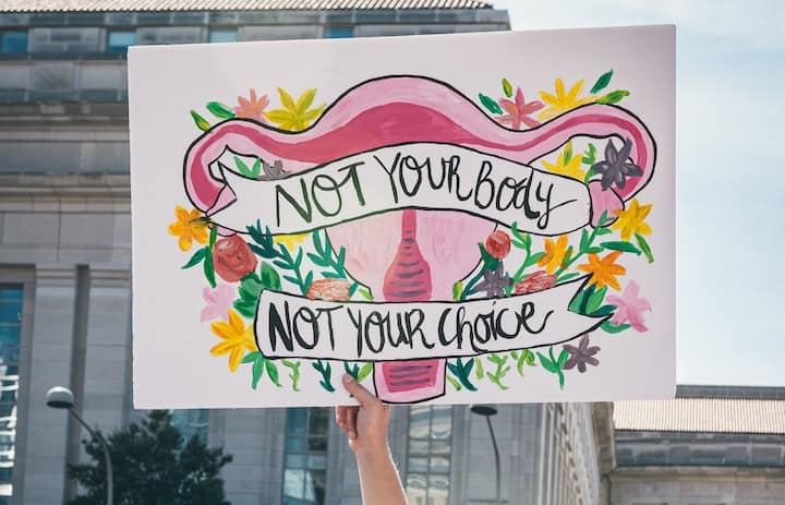 A protester holds up a sign during a march. Abortion advocates argue that the child in the womb is not a person, a separate body, or human rights.